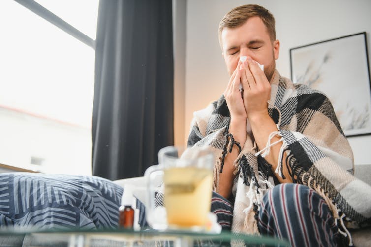 Man at home, sick with cold or flu, wiping nose