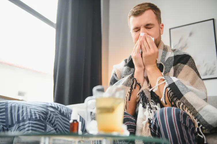 Man at home, sick with cold or flu, wiping nose