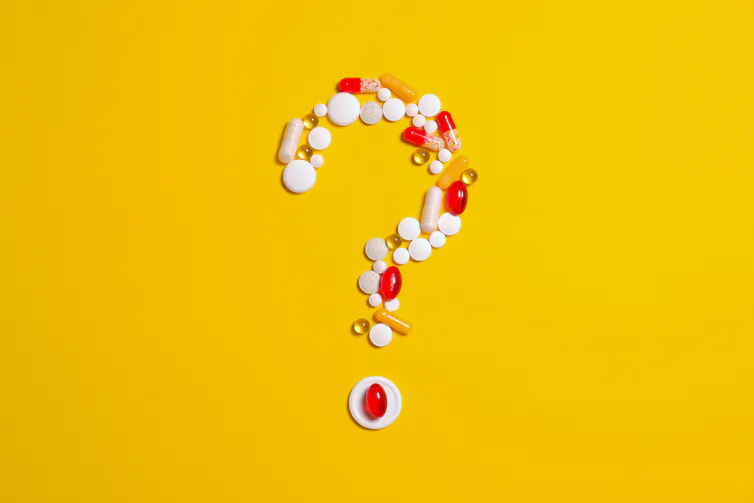 Question mark made of multivitamins on a yellow background