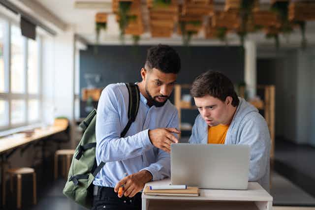 Dos estudiantes, uno con síndrome de down, observan la pantalla del ordenador.