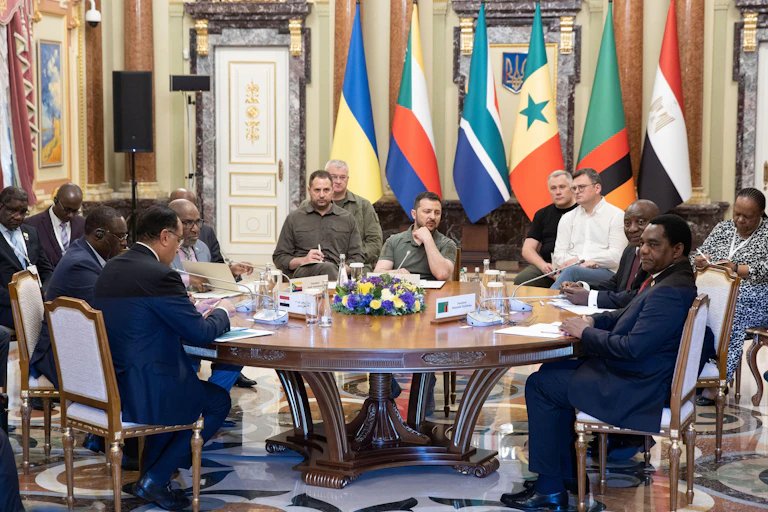 African and Ukrainian officials sit around a tabnle surrounded by their national flags.