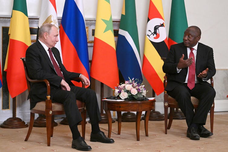 Russian president Vladimir Putin and South African president Cyril Ramaphosa, with flags of their countries in the background,