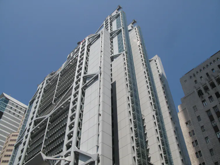 Contrapicado de un edificio alto y gris con la estructura interior a la vista.