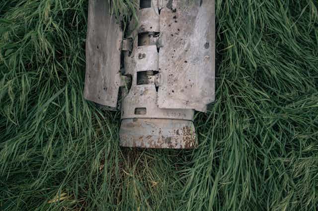 The shell of a rocket is seen lying on the grass.