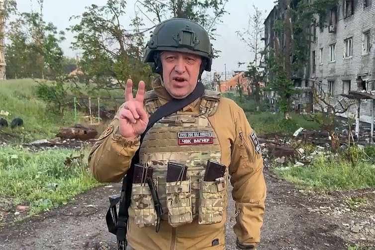 Szef Grupy Wagnera Jewgienij Prigożyn w wojskowym mundurze robi znak „v”.