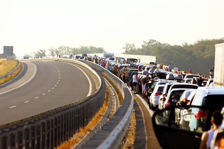 Row of cars stuck in a traffic jam under a blazing sun.