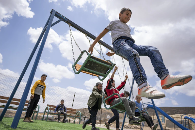 Smiling children play on a swing set.