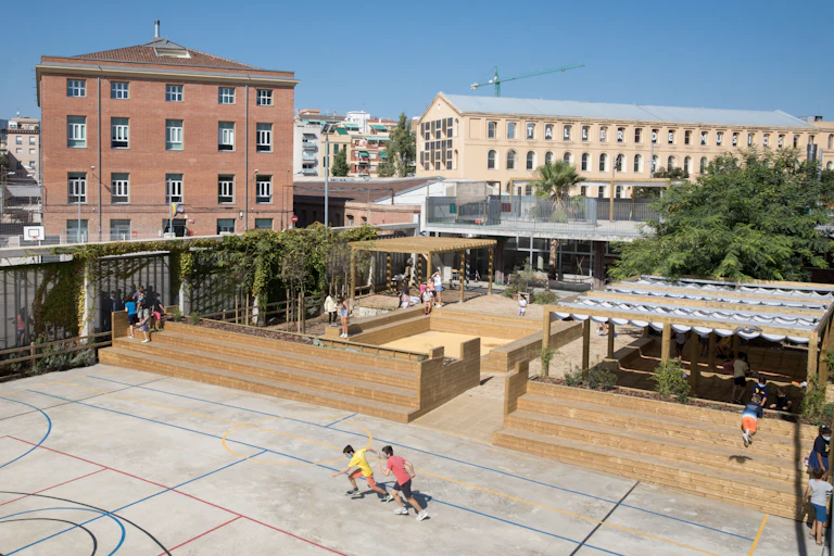 Patio de colegio con pérgolas y vegetación.