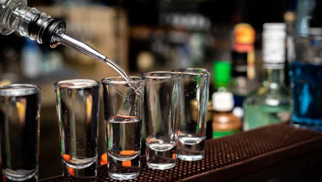 Alcohol being poured into shot glasses. 