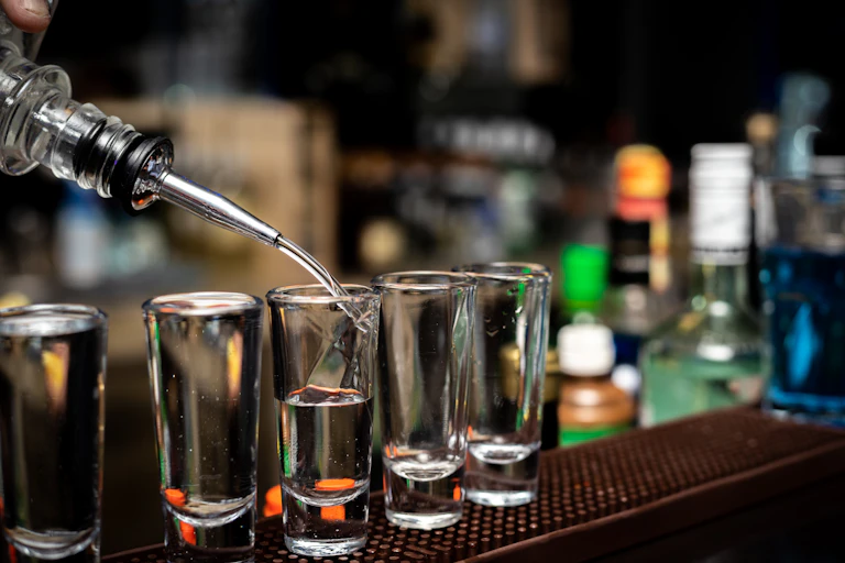 Alcohol being poured into shot glasses.