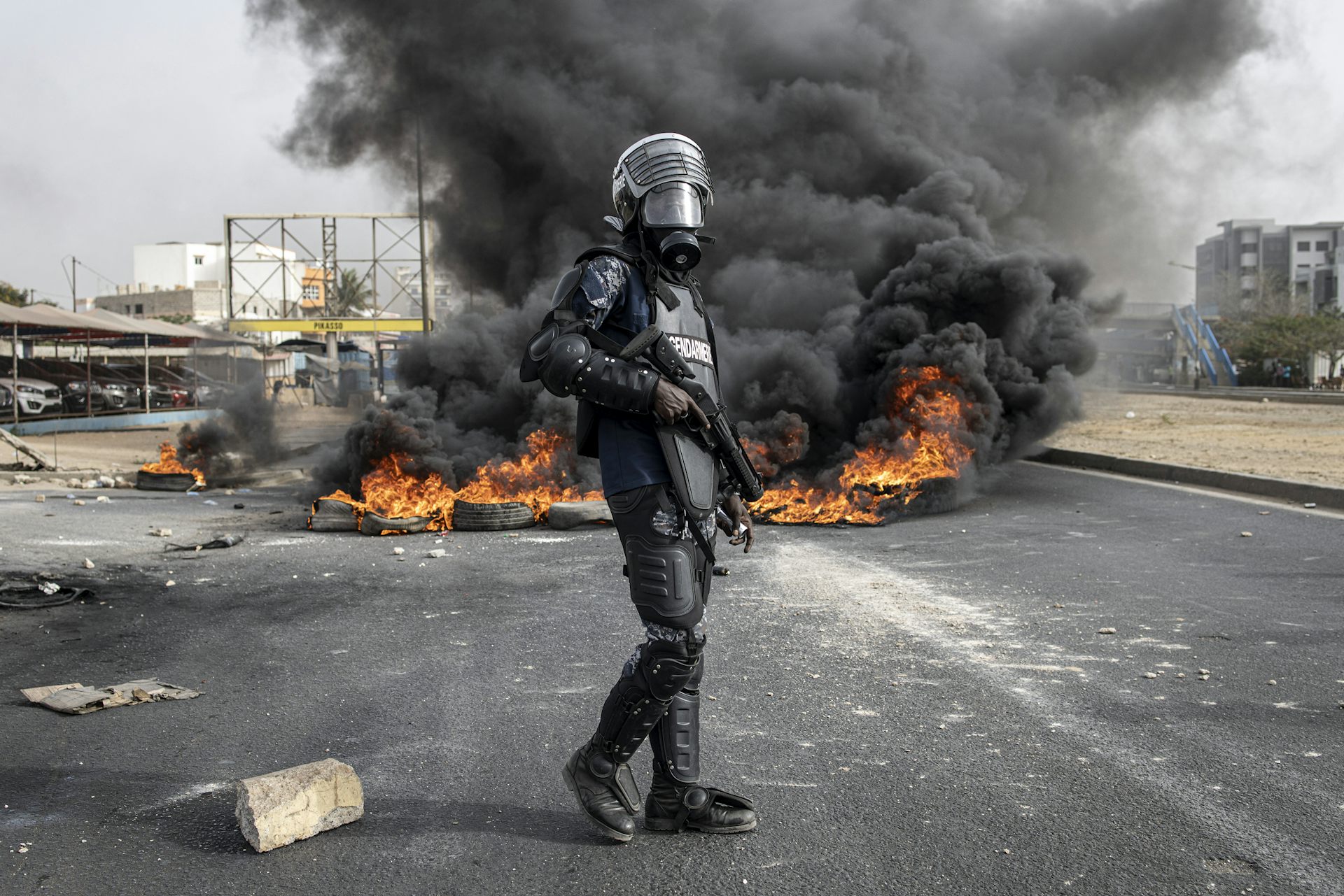 Policier séégalais devant i,e voiture en feu