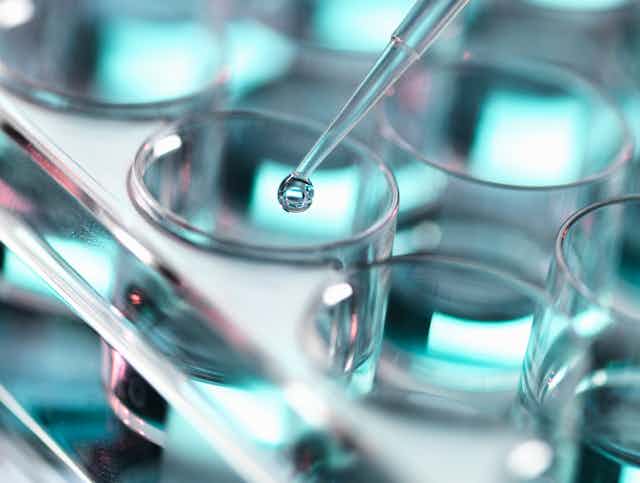 A pipette drops a liquid into the test tube.