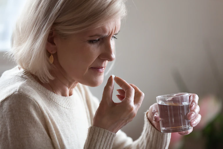 woman looks concerned, about to take pill with water