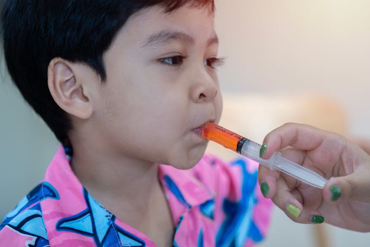 Young boy takes children's medicine in oral syringe