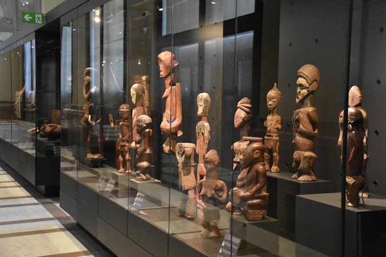 Wooden sculptures on display behind a glass case.