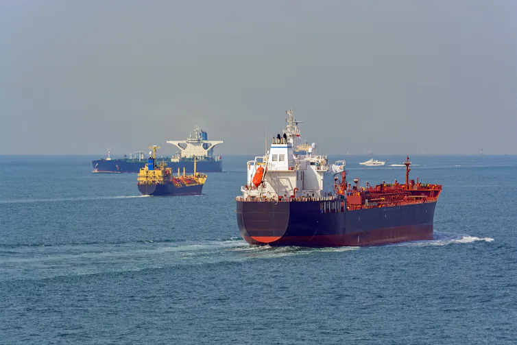 Three industrial ships pass each other on the ocean.