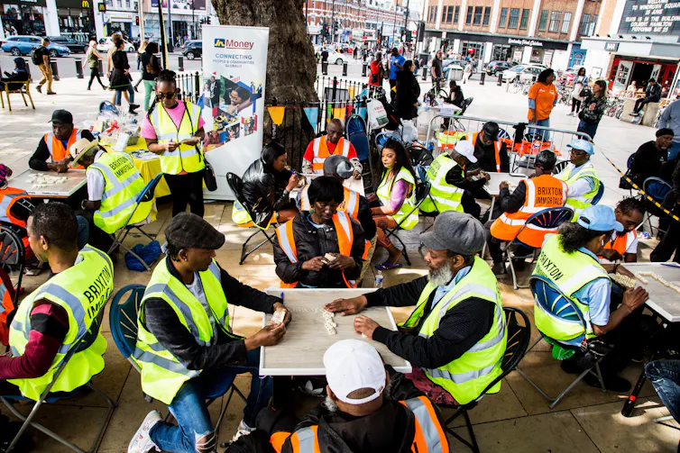 People in high-vis vests at tables on a public square.