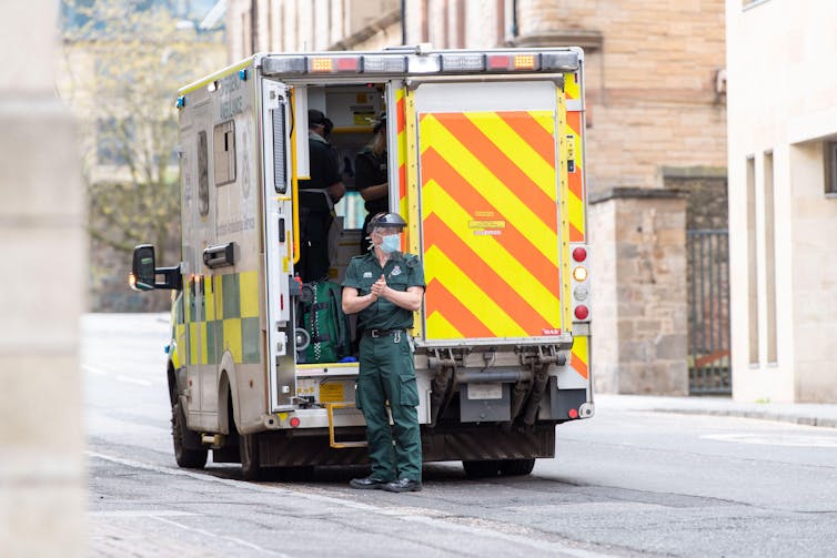 A paramedic standing beside an ambulance.