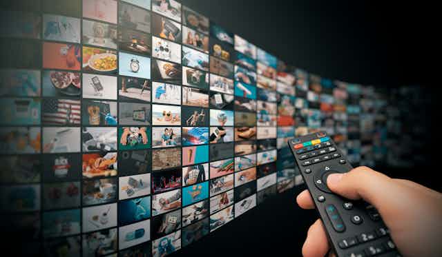 A person pointing a remote at a never ending TV screen.
