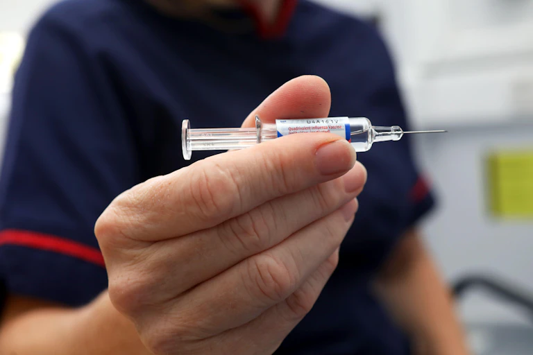 A hand holding a flu jab