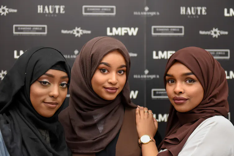 Three girls in hijabs at a fashion show.