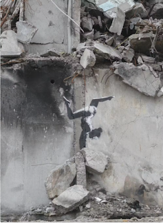 A Banksy graffiti image of a gymnast on a shelled out building in Ukraine.