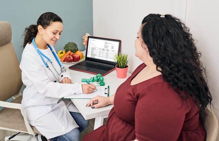 A woman speaks with her doctor in a clinic.