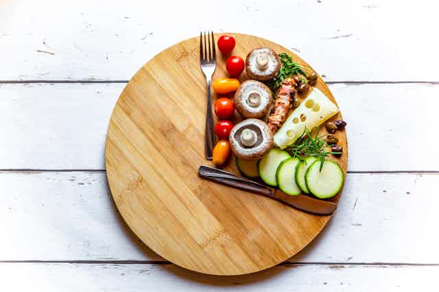 A wooden board with food and a knife and fork