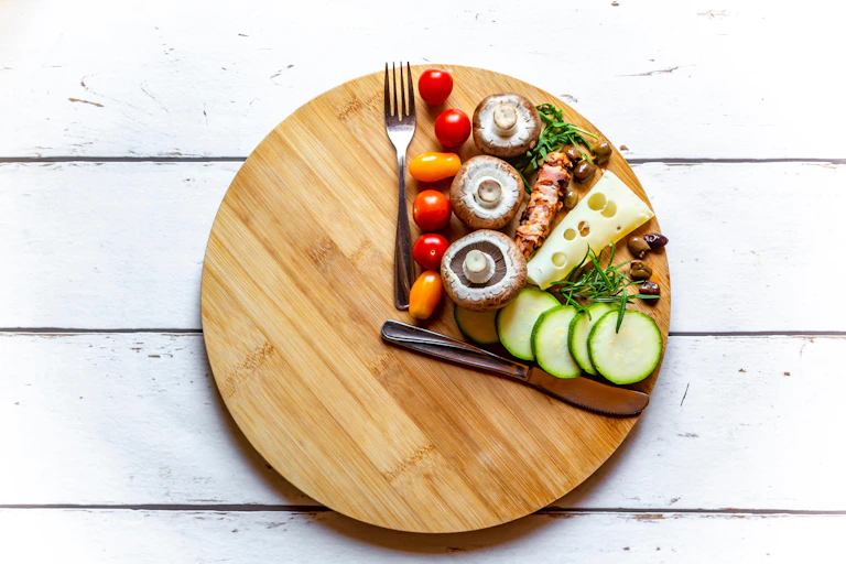 A wooden board with food and a knife and fork