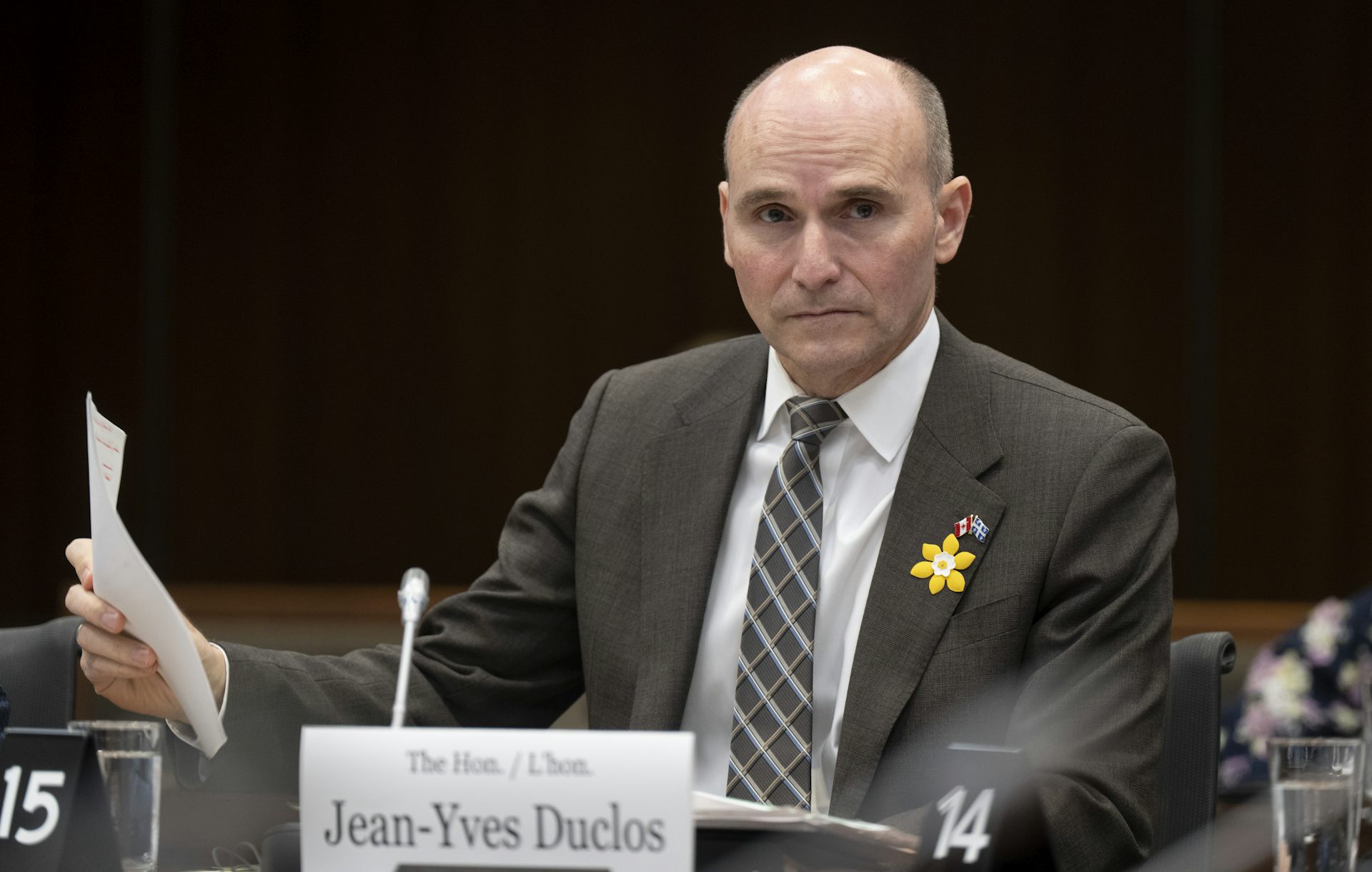 A man in a suit and a striped tie sitting at a table behind a nameplate reading Minister of Health Jean-Yves Duclos