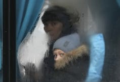 A woman and child look out the window of a bus.