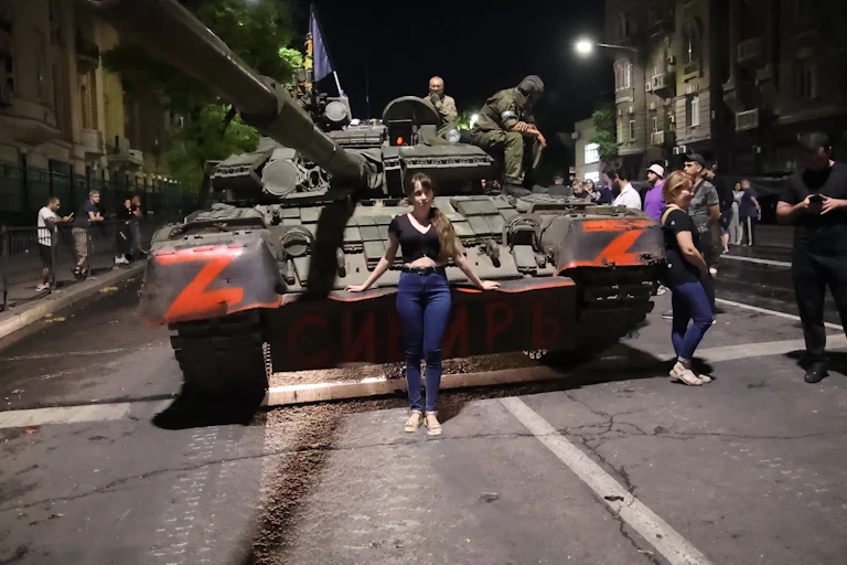 A woman poses for a photo in front of the Wagner Group military vehicle.
