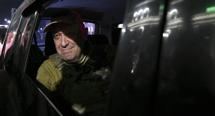 Un hombre sonriente en el asiento trasero de un coche.