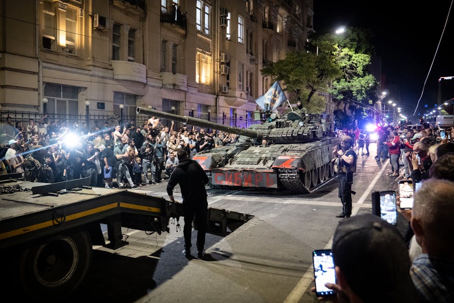 Des chars dans une ville la nuit, salués par les habitants