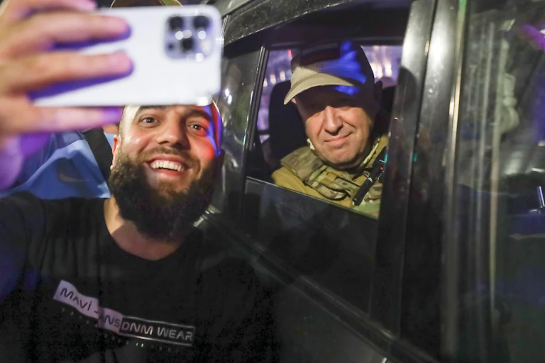 A bearede man takes a selfie with Wagner Group boss Yevegency Progizhin in the background,