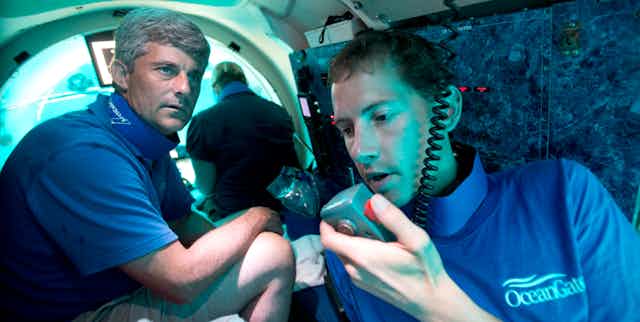 Submersible pilot Randy Holt, right, communicates with the support boat as he and Stockton Rush, left, CEO and Co-Founder of OceanGate, dive in the company's submersible, "Antipodes," about three miles off the coast of Fort Lauderdale, Florida, June 28, 2013