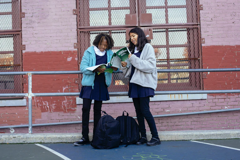 Two students look at text books in a playground.