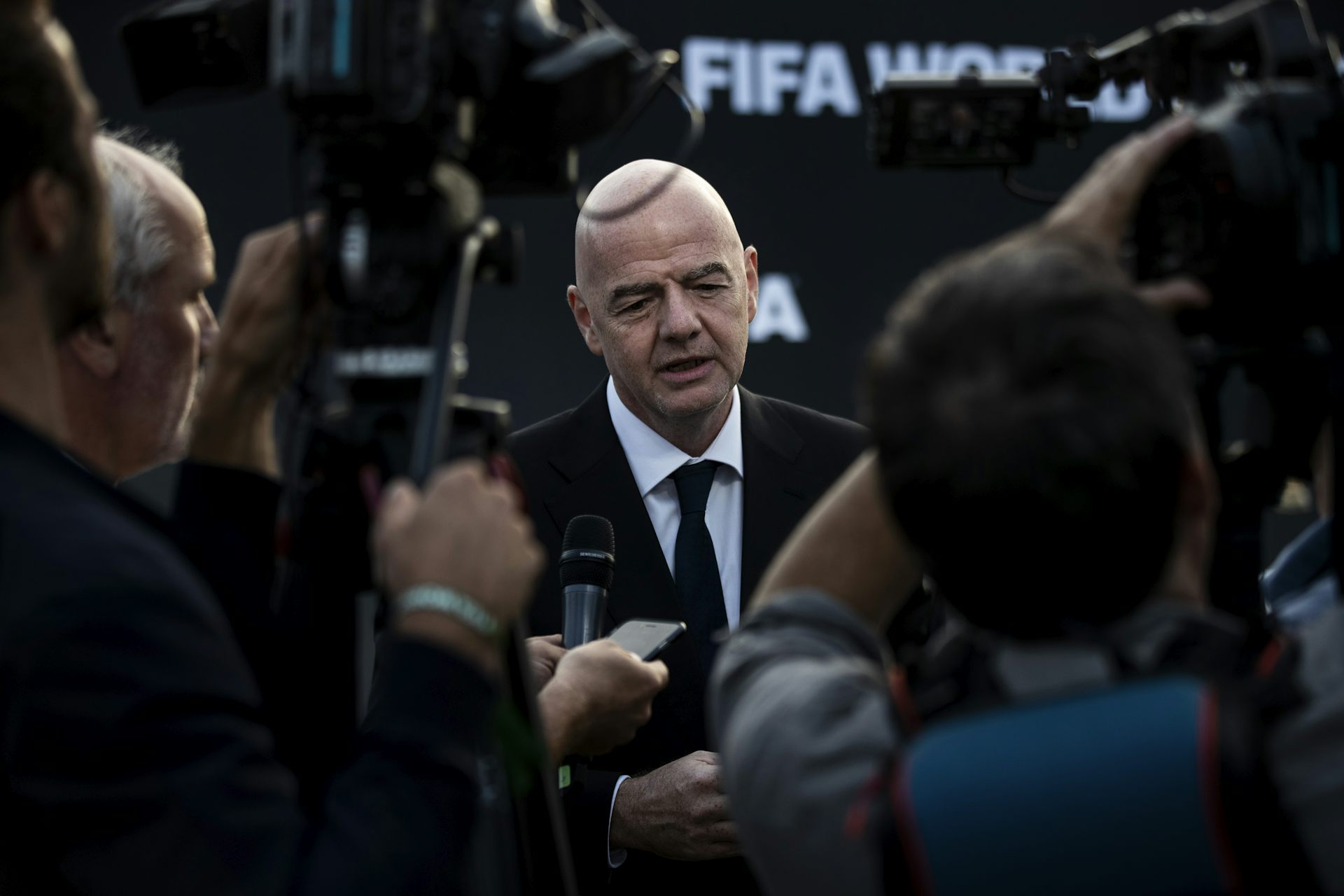 Fifa President Gianni Infantino wearing a black suit, surrounded by journalists.