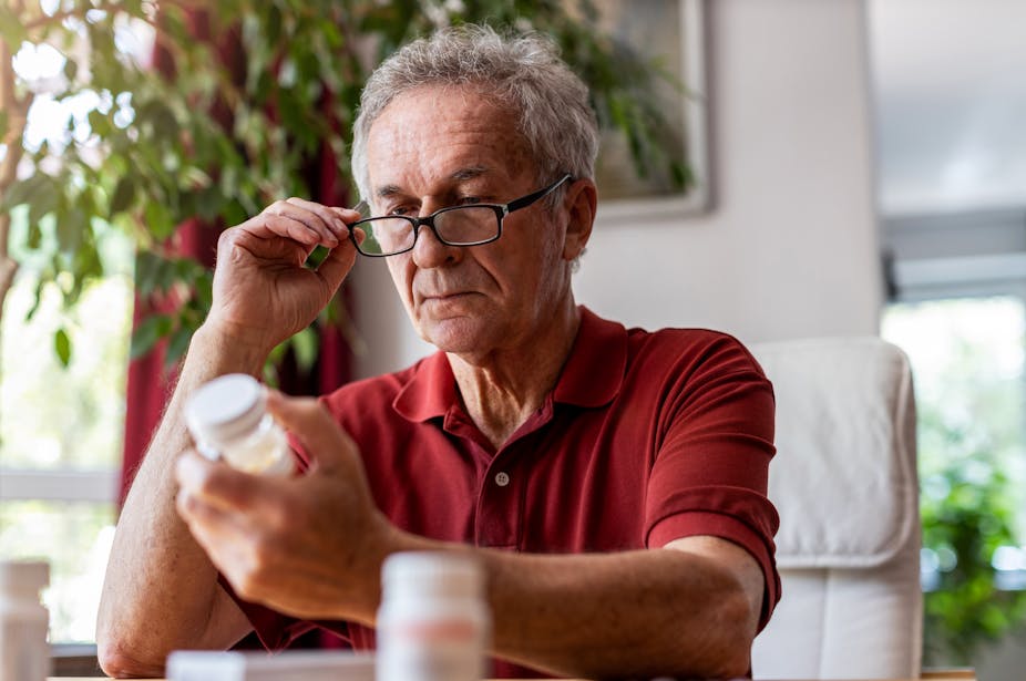 A man looks at a jar of pills.
