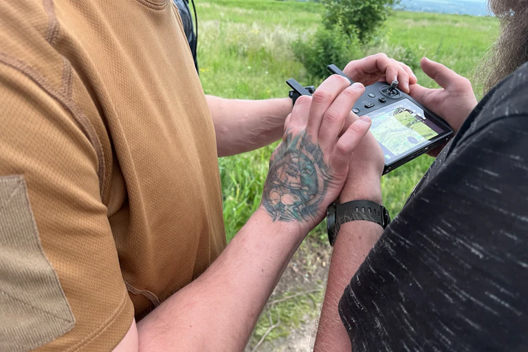Deux hommes dont on ne voit que les mains manipulent une télécommande drone