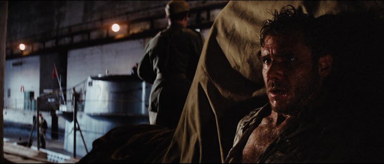Un hombre medio desvestido y sangrando se oculta detrás de una montaña de cosas (Harrison Ford en Indiana Jones ).