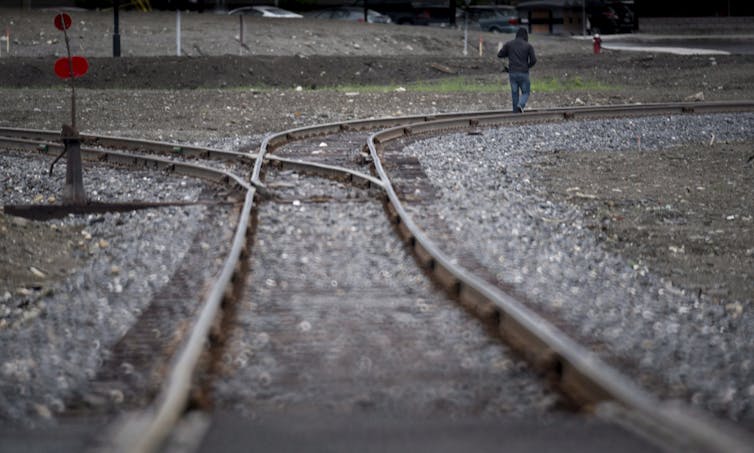 A man walks along train tracks.