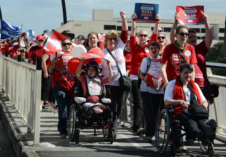 protestors on bridge in red shirts, some in wheelchairs