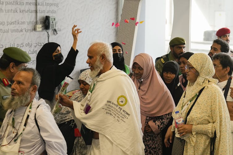 Female police officer welcoming Hajj pilgrims with rose petals in Jeddah, Saudi Arabia