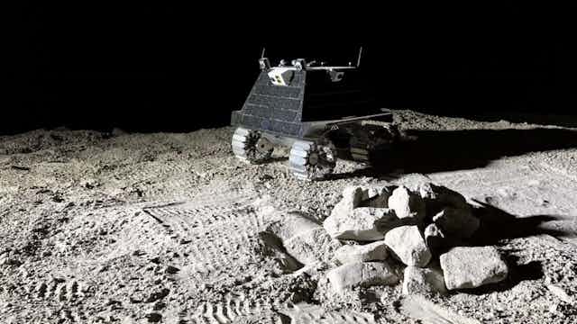 A phot of a small four-wheeled robotic vehicle in a moon-like landscape