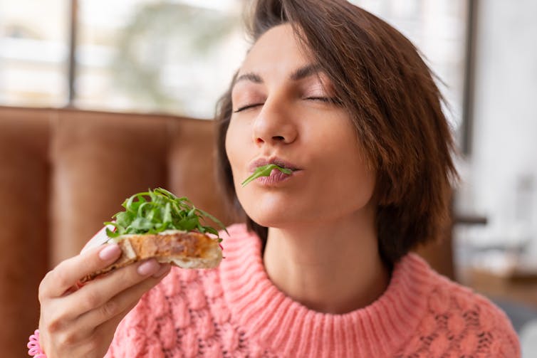 woman bites bread with topping