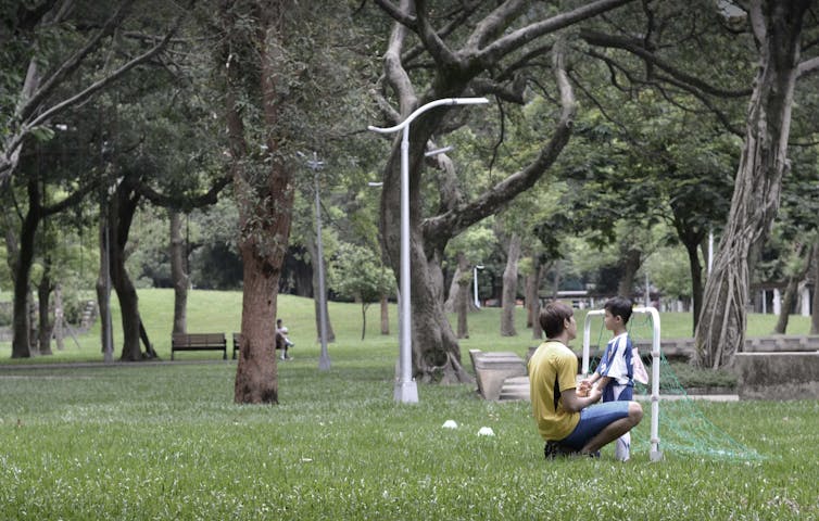 A man and child talk in a park.