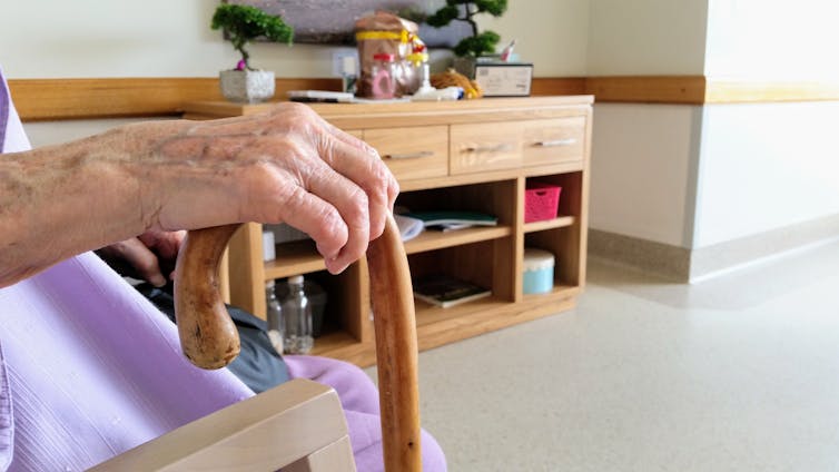 Older person holds walking stick