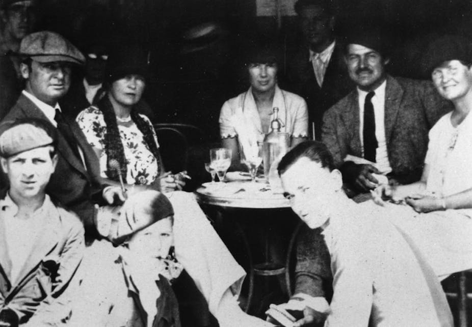 A group of people sit around a table in a cafe in the mid-20s.