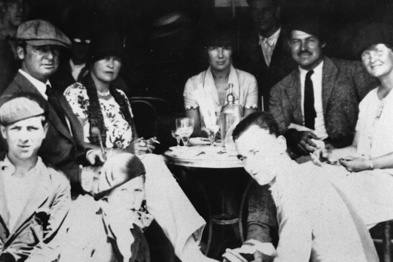 A group of people sit around a table in a cafe in the mid-20s.